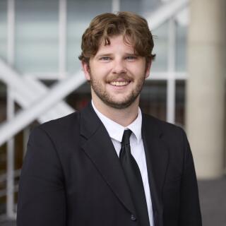 male, brown hair, beard in a suit