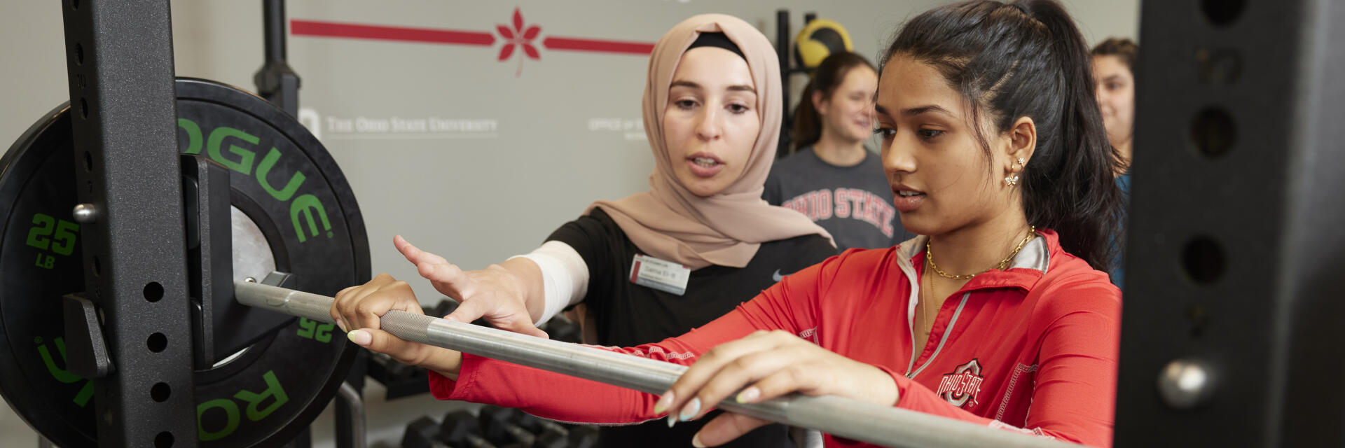 Trainer teaching individual how to use barbell