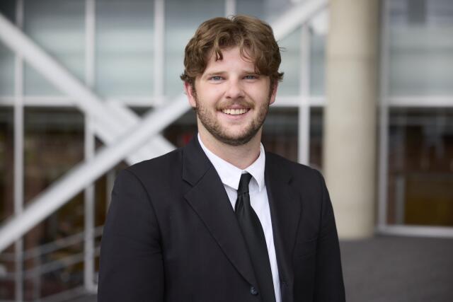 male, brown hair, beard in a suit